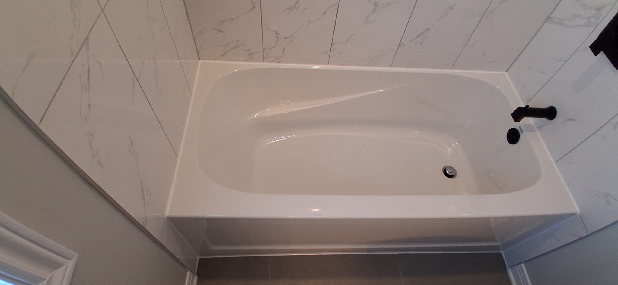 Fresh white caulking applied along a bathtub edge in Ottawa after old sealant removal and joint preparation.