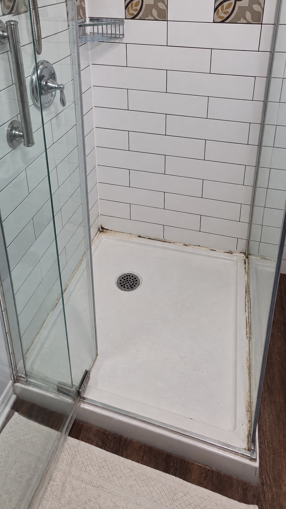 Shower base with deteriorated caulking before replacement